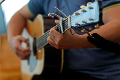 Midsection of guitarist playing acoustic guitar