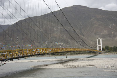 View of suspension bridge against cloudy sky