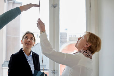 Real estate agent looking at senior couple taking measurements in new house