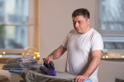 Man ironing clothes at home