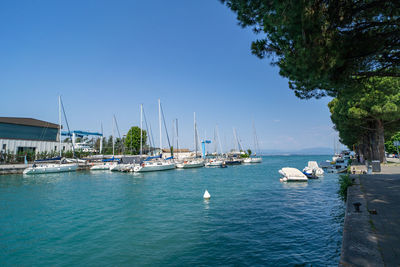 Boats in sea against clear blue sky