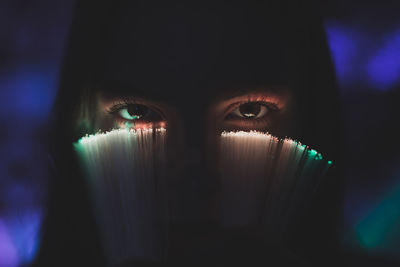 Close-up portrait of young woman holding illuminated fiber optic