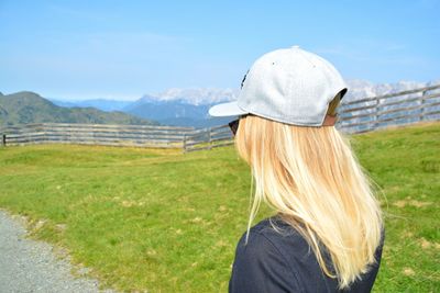 Rear view of woman standing on field against sky