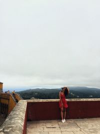 Rear view of woman standing on mountain against sky