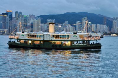 Sailboats in sea by city against sky