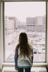 Rear view of girl standing in front of apartment window