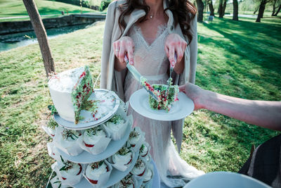 Low section of woman serving slice of cake at park