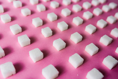 Close-up of sugar cubes arranged on pink table