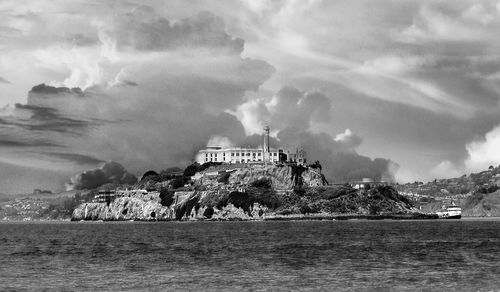 Building by sea against cloudy sky