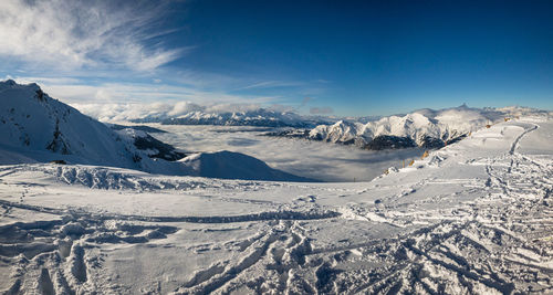 Scenic view of snow covered mountains and sea of fog against blue sky