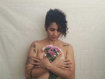 Beautiful shirtless woman holding bouquet of flowers