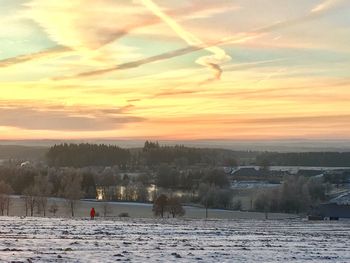 Scenic view of landscape against dramatic sky during sunset