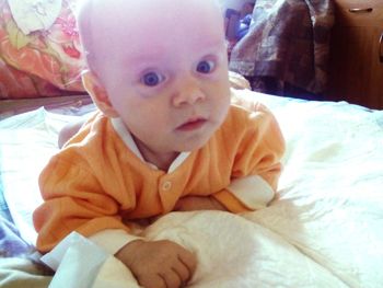 Portrait of cute baby relaxing on bed at home