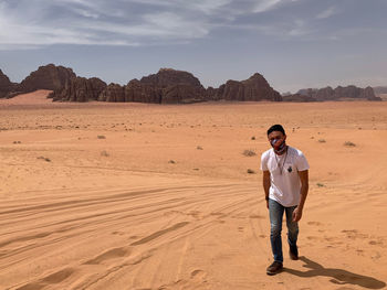 Full length portrait of man standing on desert