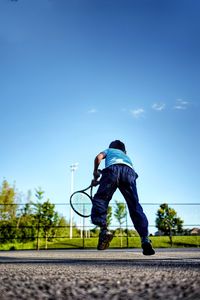 Surface level shot of boy playing with racket on road