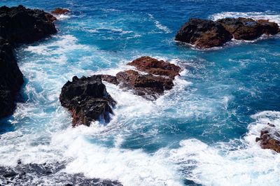 High angle view of waves splashing and crashing  on and over rocks white water surf 