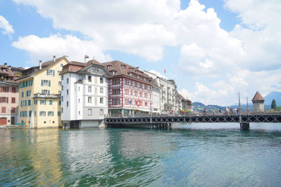 Buildings by river against sky