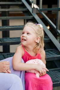 Portrait of young woman sitting on railing