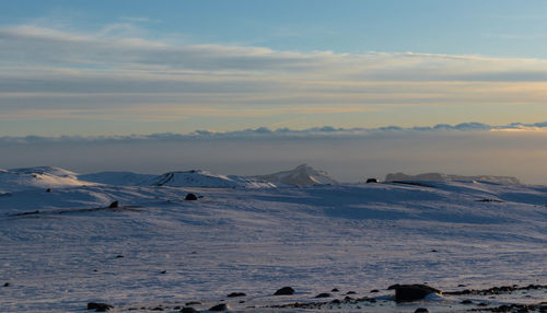 Scenic view of frozen landscape against sky during sunset