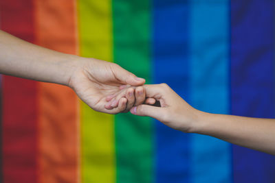 Cropped image of man holding hands against multi colored background