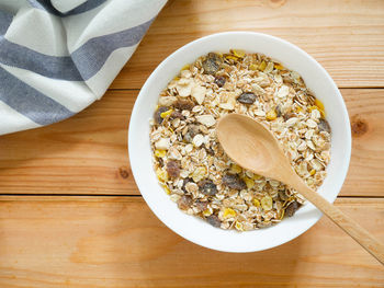 A bowl of muesli breakfast and rolled oats with dried fruits on wooden table. top view.