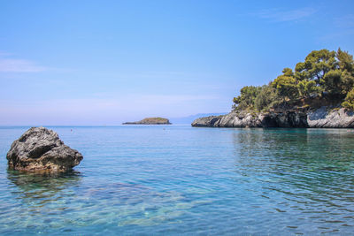 Rock formation in sea against blue sky