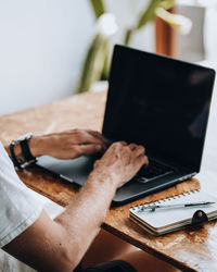 Midsection of man using laptop on table