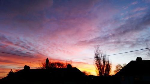 Low angle view of silhouette trees against dramatic sky