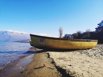 Boat moored on beach against sky