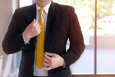 Midsection of businessman holding his blazer in office
