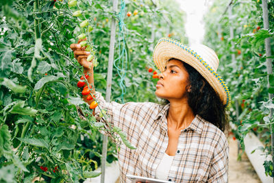 Side view of young woman wearing hat standing against trees