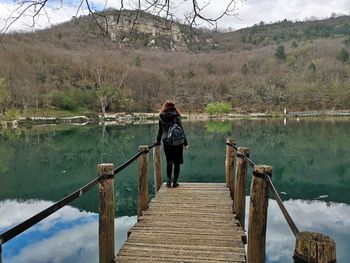 Rear view of woman standing on pier over lake