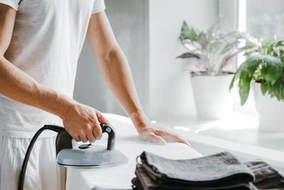 Midsection of woman holding hands while standing in kitchen