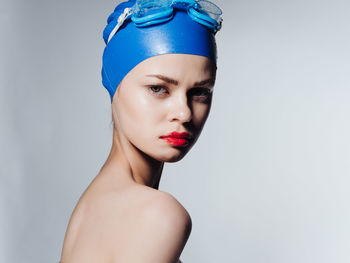 Portrait of young woman against blue background