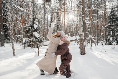 Mother and daughter playing in the winter sunny forest. high quality photo
