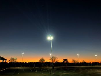 Illuminated road against sky at night