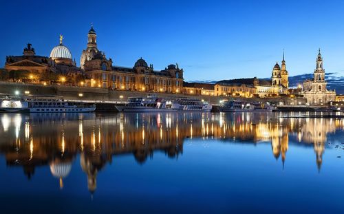 River by illuminated buildings and dresden cathedral at dusk