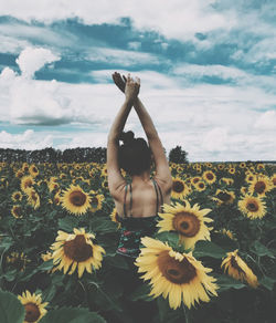 Midsection of woman with yellow flowers against sky