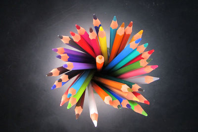 High angle view of multi colored pencils on table against black background