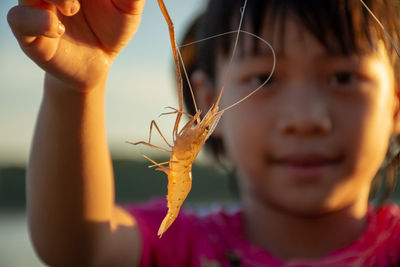 Smiling girl holding shrimps at lake