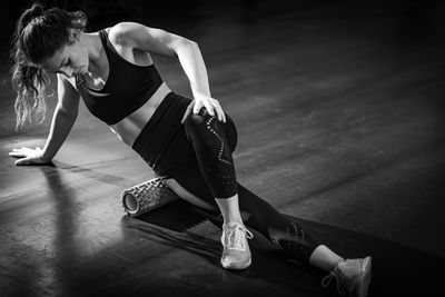 Woman using foam roller to self-massage muscles in the gym