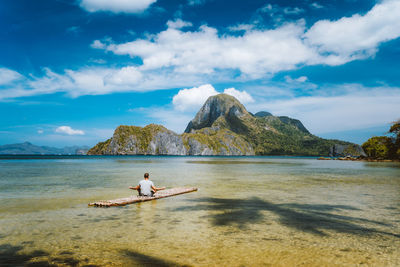 Man relaxing in sea against sky