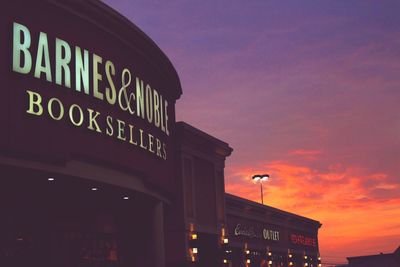 Low angle view of illuminated building against sky at sunset