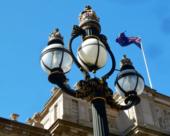 Low angle view of lamp post and australian flag against blue sky