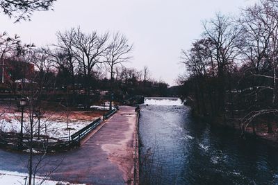 River amidst bare trees against clear sky