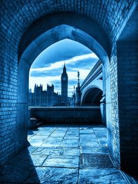 Big ben seen through arch against cloudy sky