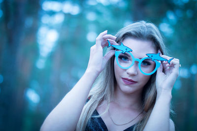 Portrait of young woman wearing eyeglasses against trees