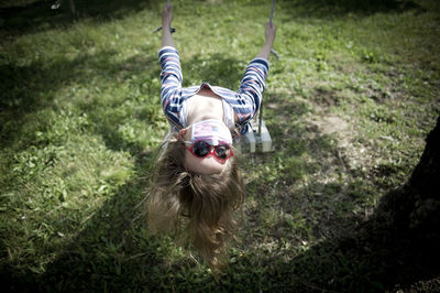 Little girl swinging in the garden with surgical mask