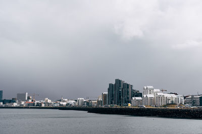 Sea by buildings against sky in city