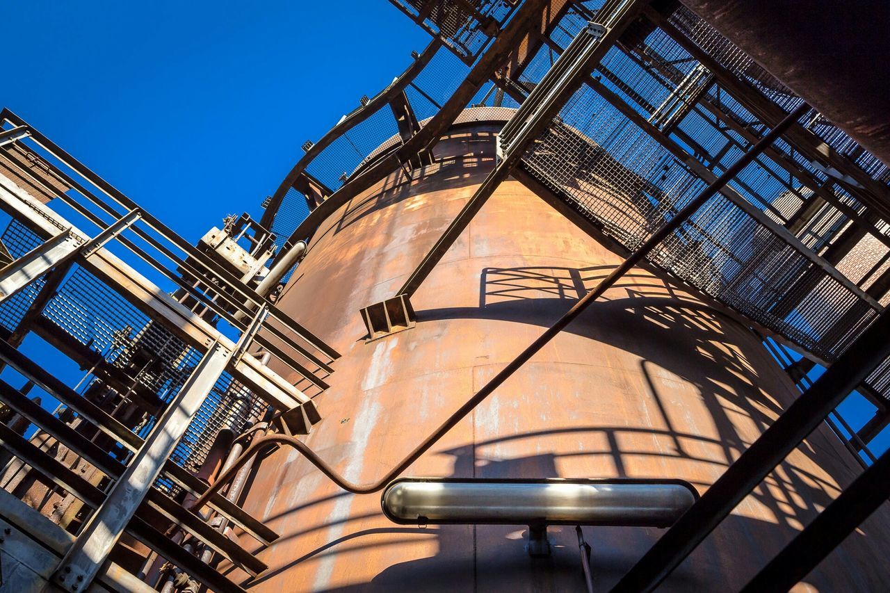 low angle view, architecture, built structure, building exterior, metal, sky, no people, clear sky, lighting equipment, metallic, building, day, indoors, tower, travel destinations, sunlight, architectural feature, illuminated, blue